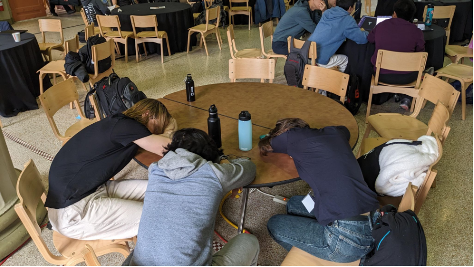 the team of hackers sleeping while sitting around the table at the hackathon