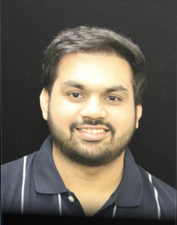 Headshot of a person in a black background with a smile wearing a navy blue tshirt with stripes