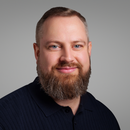 Headshot of Brandon Kindred (CAA), a white man with short hair, a beard and wearing a black shirt