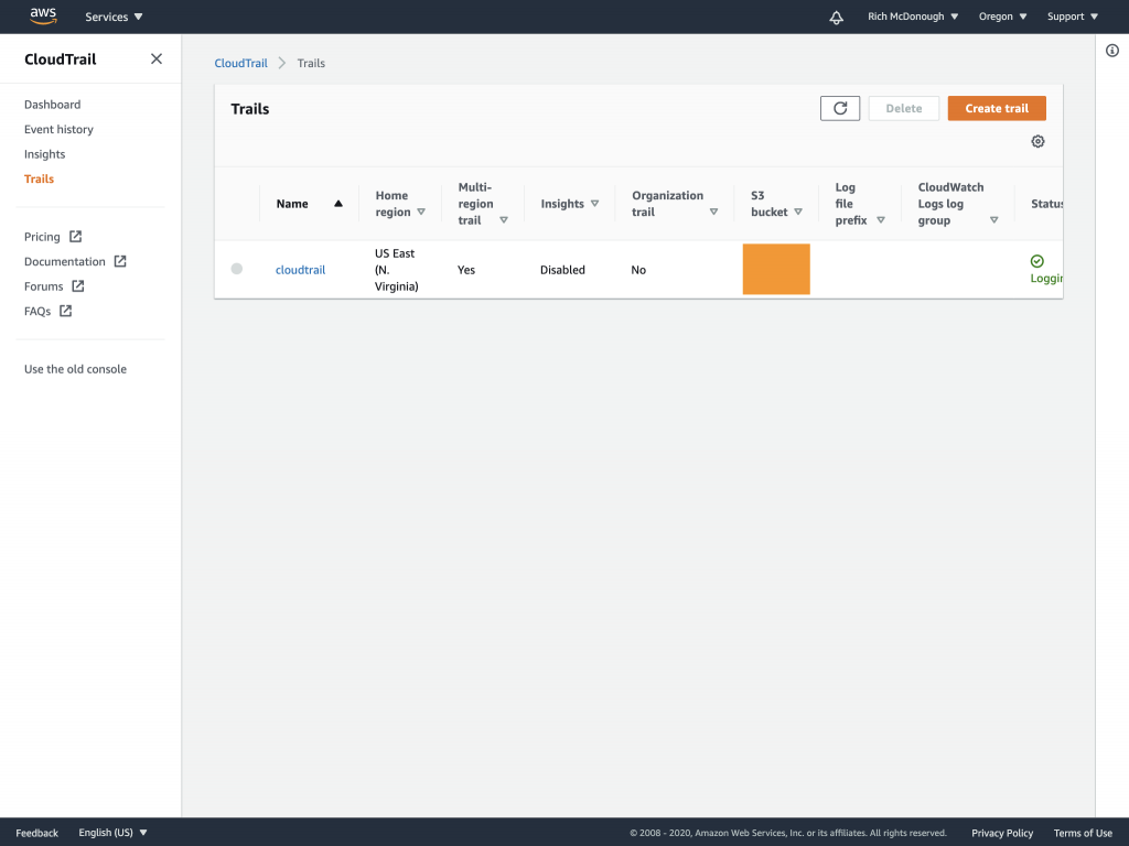 Trails page in the CloudTrail console displays columns for trail name, home Region, multi-Region trail, insights, organization trail, S3 bucket, log file prefix, log group, and status.