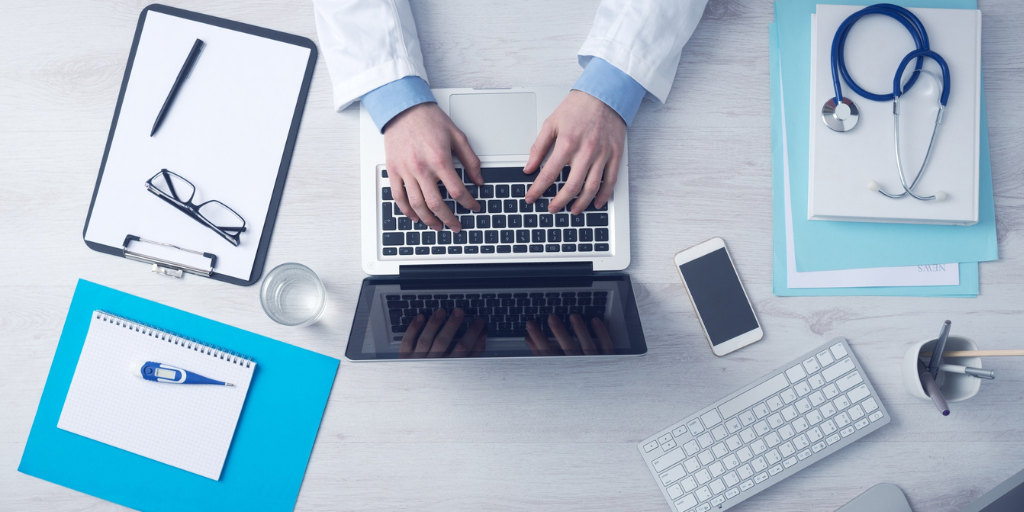 aerial photo of doctor on laptop at desk with stethescope and chart
