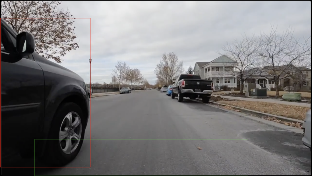 A red bounding box identifies a vehicle, while a green bounding box identifies the location of the bicycle. The boxes overlap, showing the vehicle is too close to the bicycle.