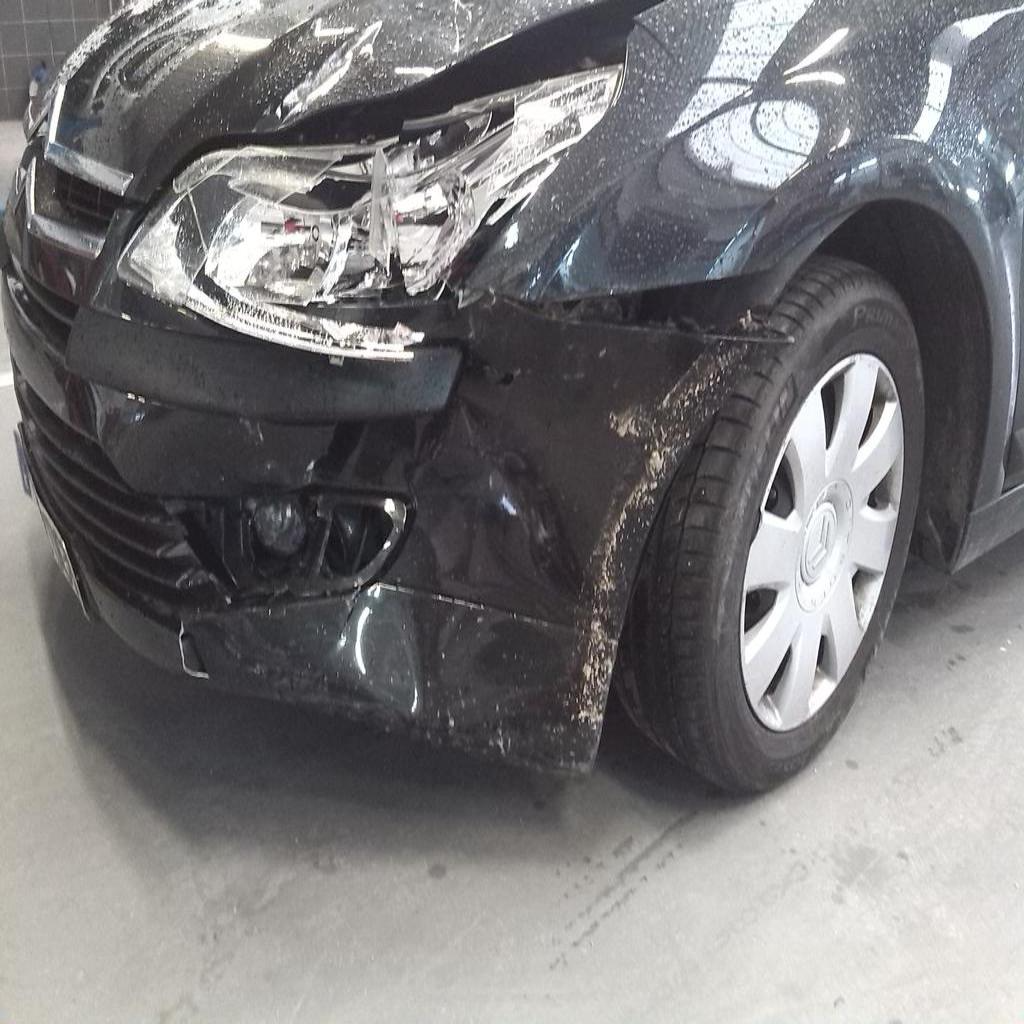 Significant impact damage visible on vehicle's front end, showing crumpled bodywork and misaligned panels