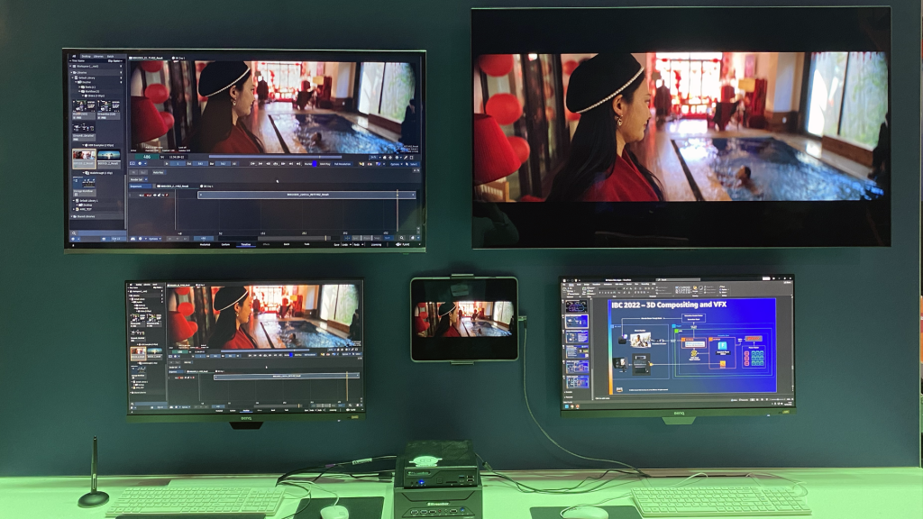 Multiple monitors mounted on a wall in the IBC exhibit hall, showing the Flame interface, a reference preview, architecture diagram and the same reference preview on a tablet. Below the monitors are two small pieces of hardware which are driving the entire display