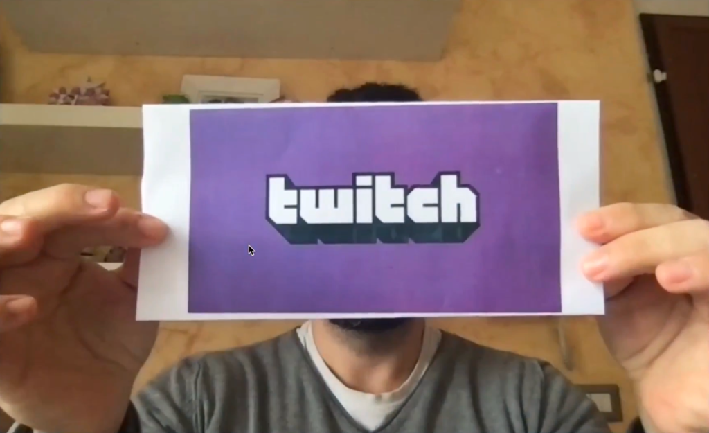 Person holding piece of paper with Twitch logo on it.
